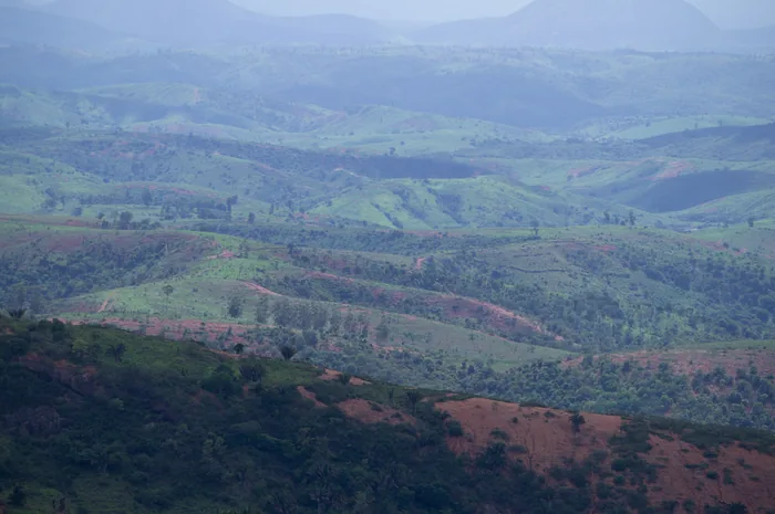 A panoramic view of rolling green hills under a partly cloudy sky.